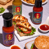 Assorted Fumami sweet and spicy fermented hot sauce bottles with food items on a table