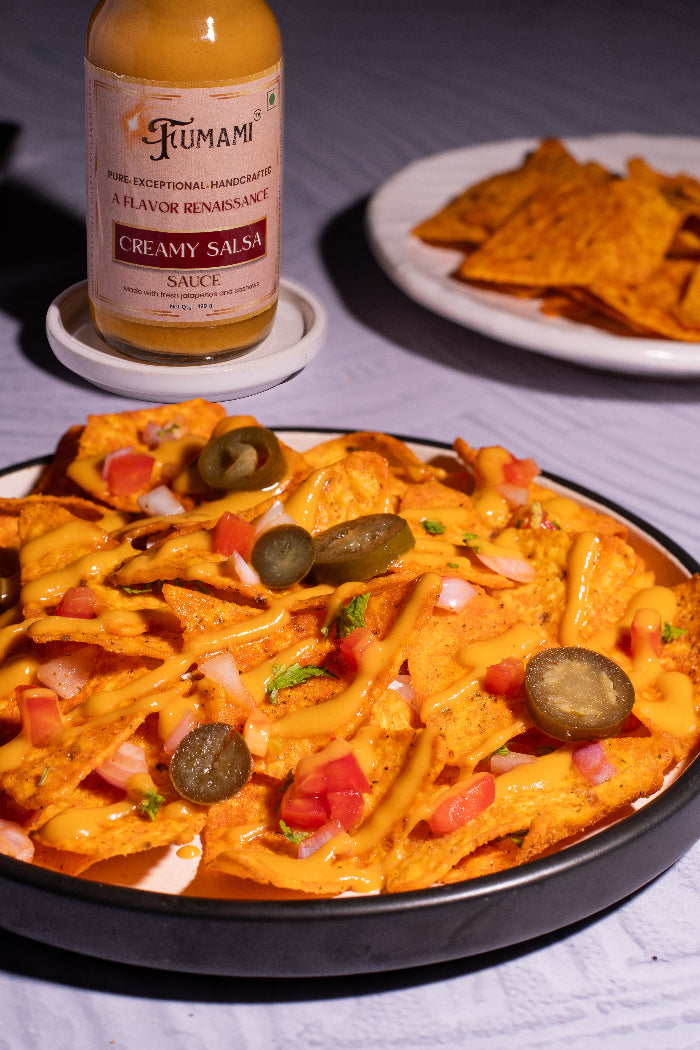 Nacho dish with Fumami creamy salsa sauce, tortilla chips, and a bottle of Fumami creamy salsa on a white surface.
