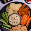 Platter of chips, vegetables, and crackers with a bowl of Fumami Onion Herb dip, and a bottle of Fumami Onion Herb sauce  in the background.