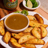 Platter of potato wedges with a bowl of Fumami sweet and spicy fermented tropical ketchup sauce and a bottle of fumami on a wooden surface.